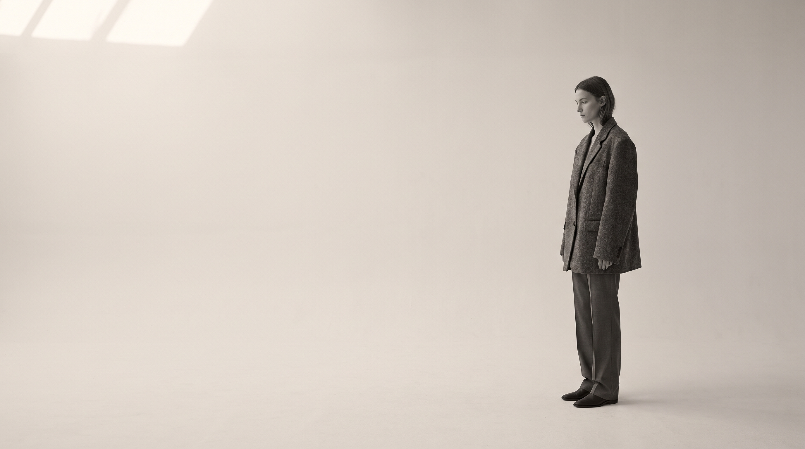 A model in profile on the seamless grey studio, negative space left